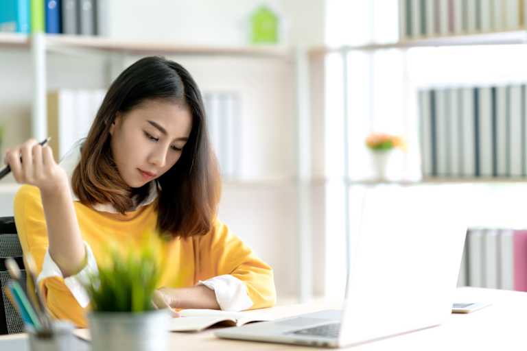 Student taking notes with laptop