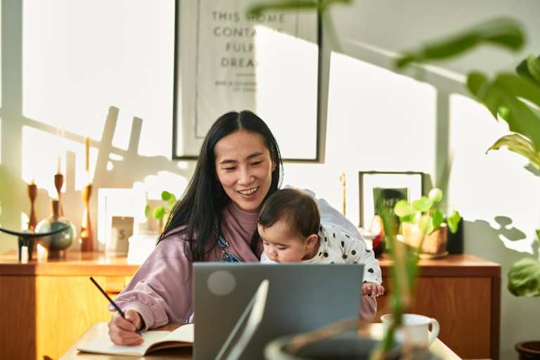 Mom holding baby on her lap while working on laptop